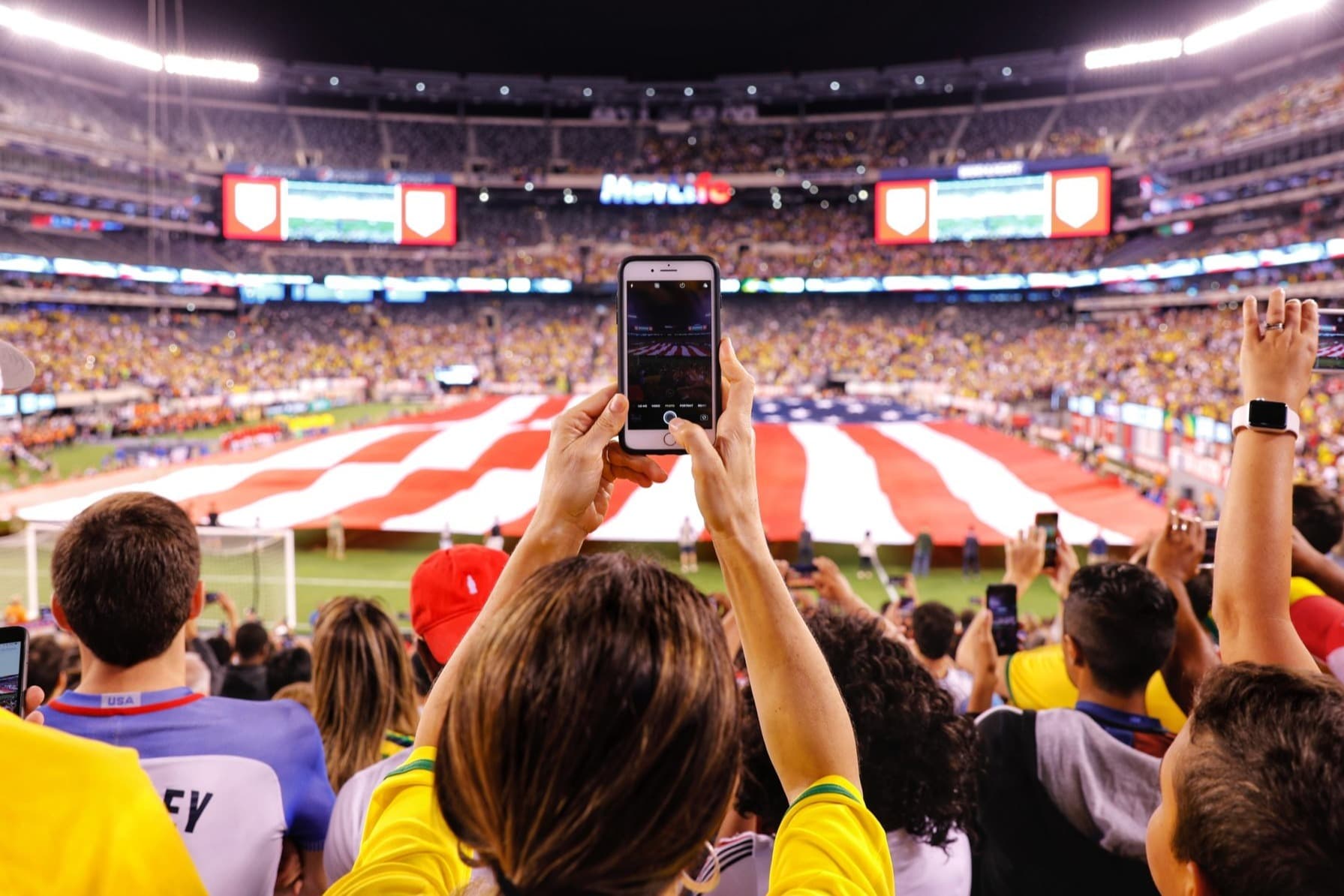 A boy taking a picture of a football stadium