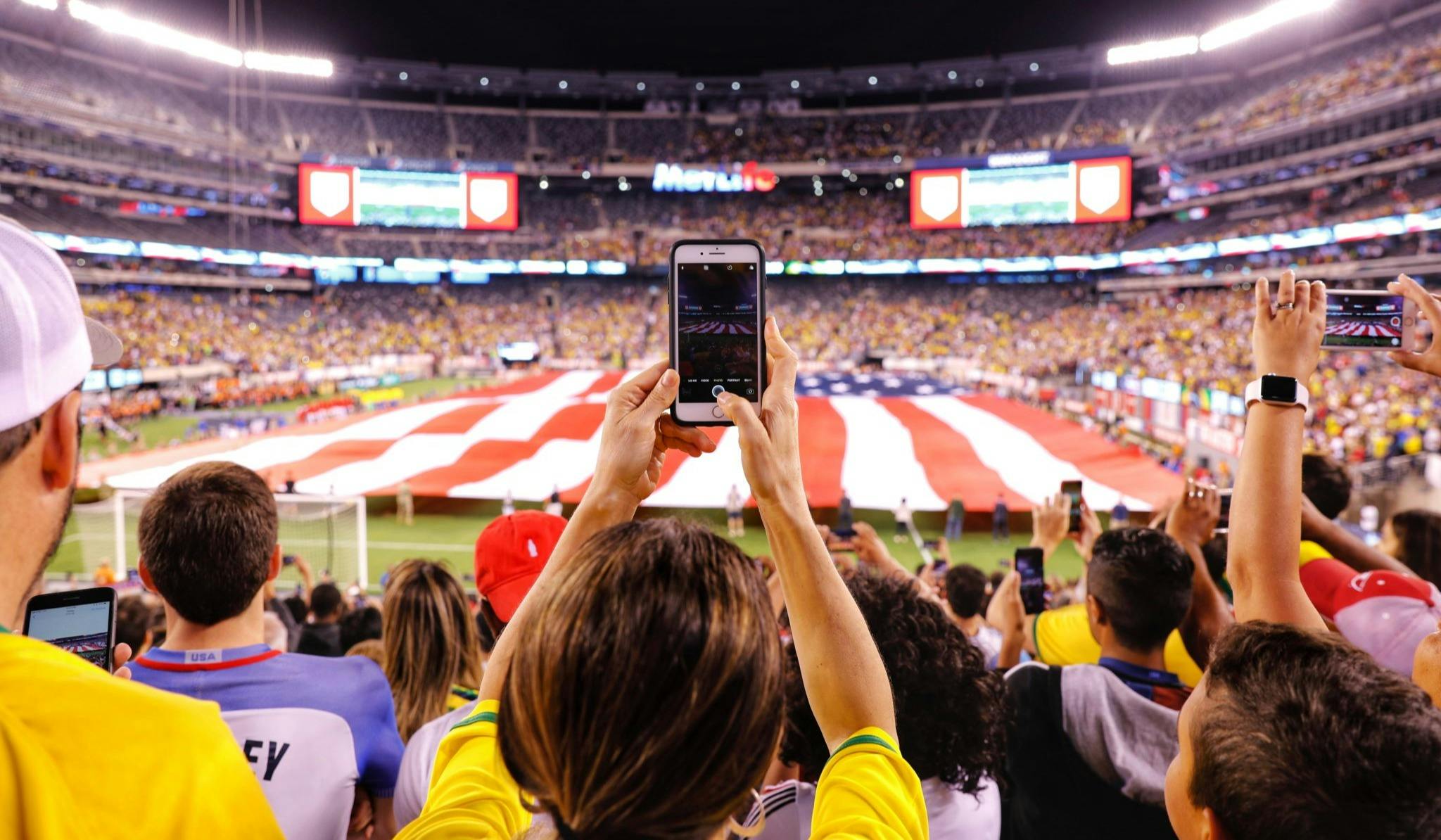 A boy taking a picture of a football stadium