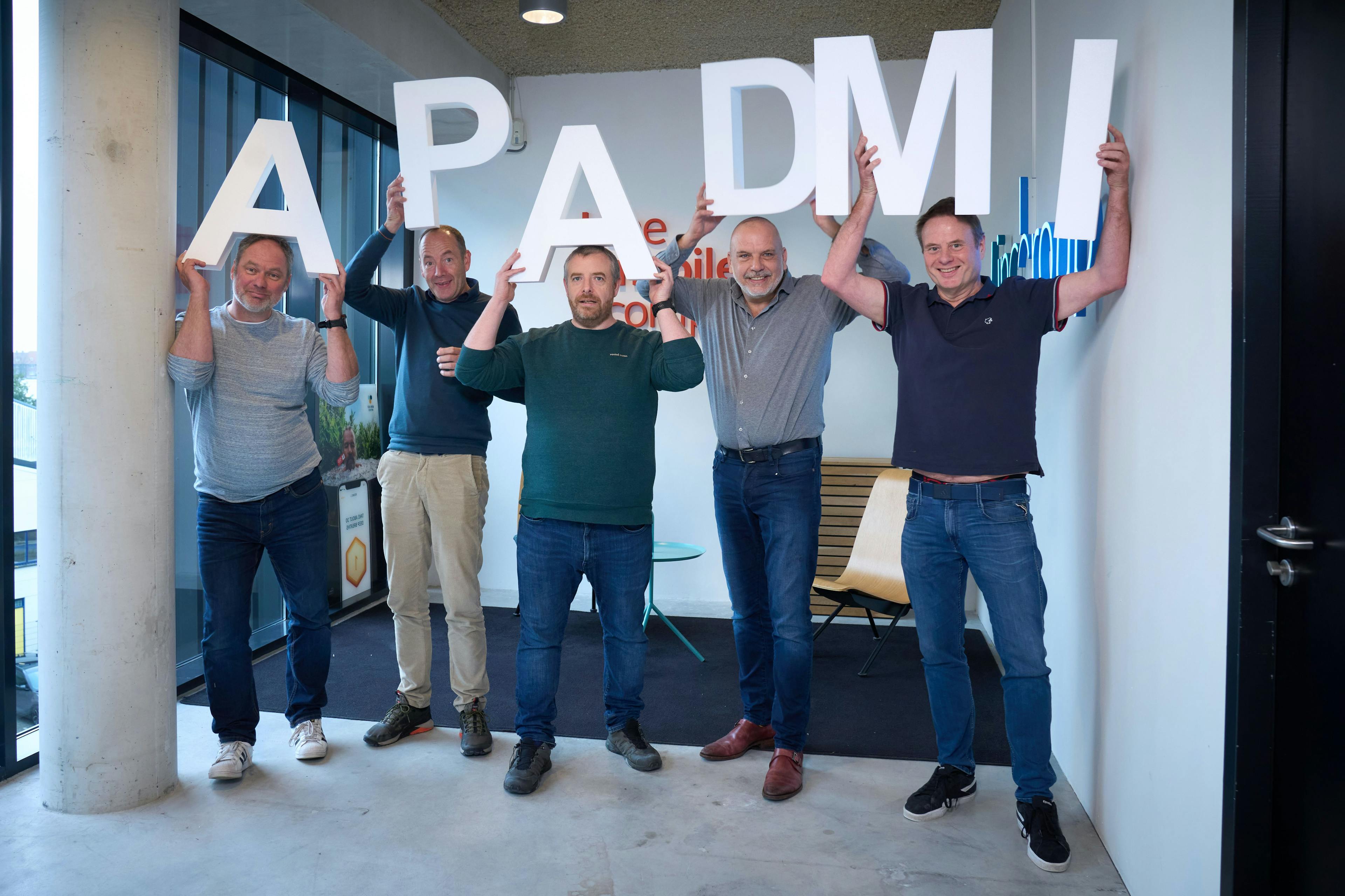 Apadmi + The Mobile Company team holding the apadmi logo