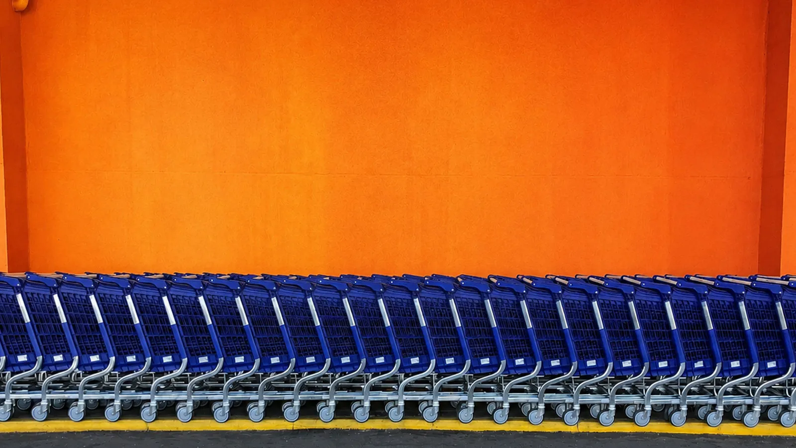 Blue shopping trolleys against an orange wall.