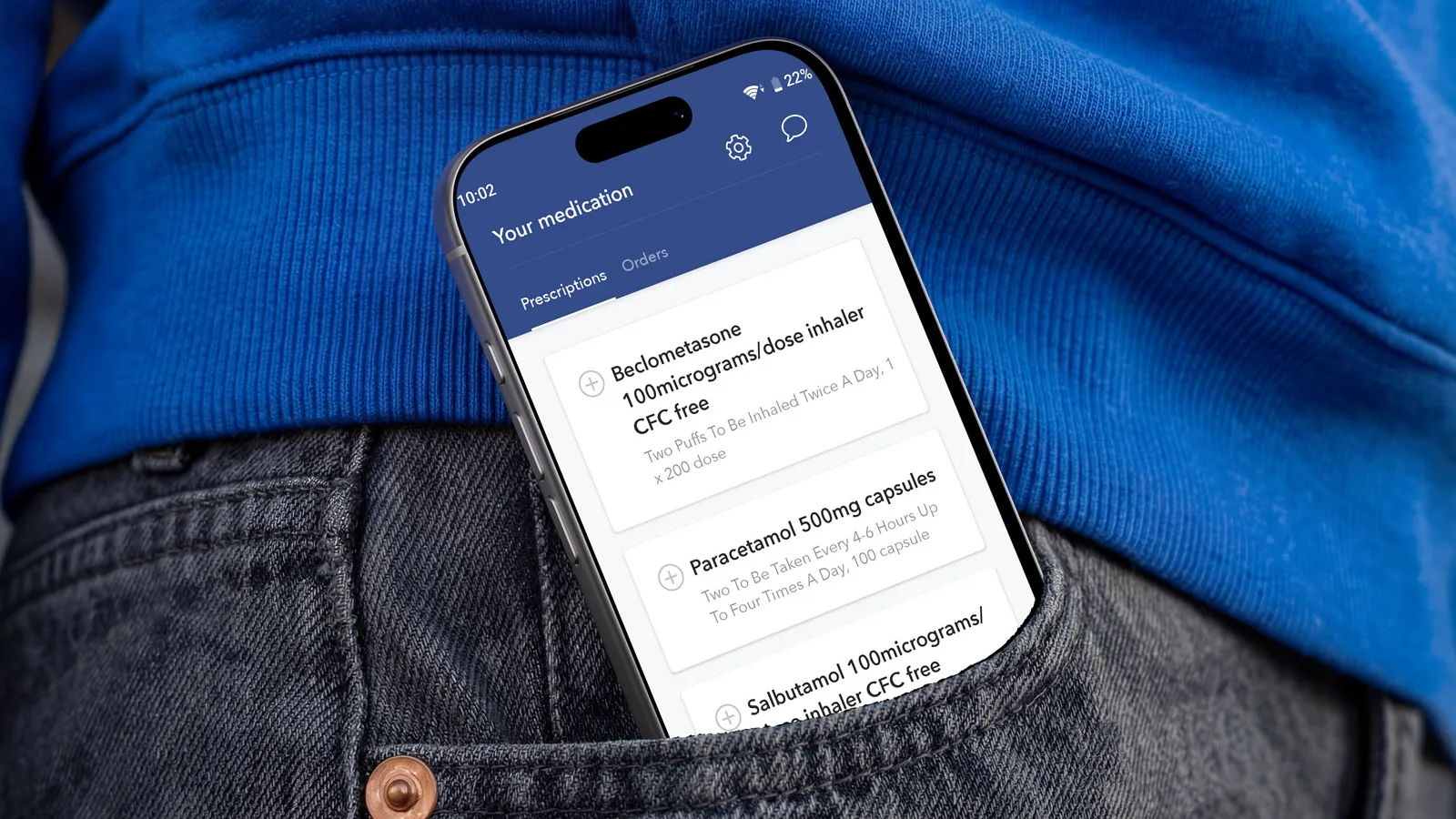 A phone showing the Hey Pharmacist app peeks out of the pocket of a pair of men's black jeans.