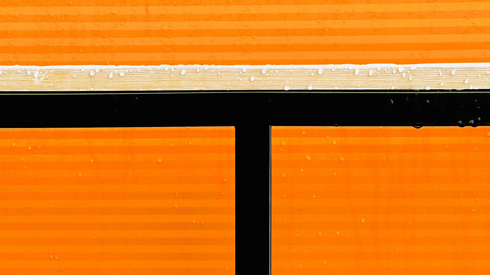 Close-up abstract image of bright orange textured panels separated by black geometric lines.