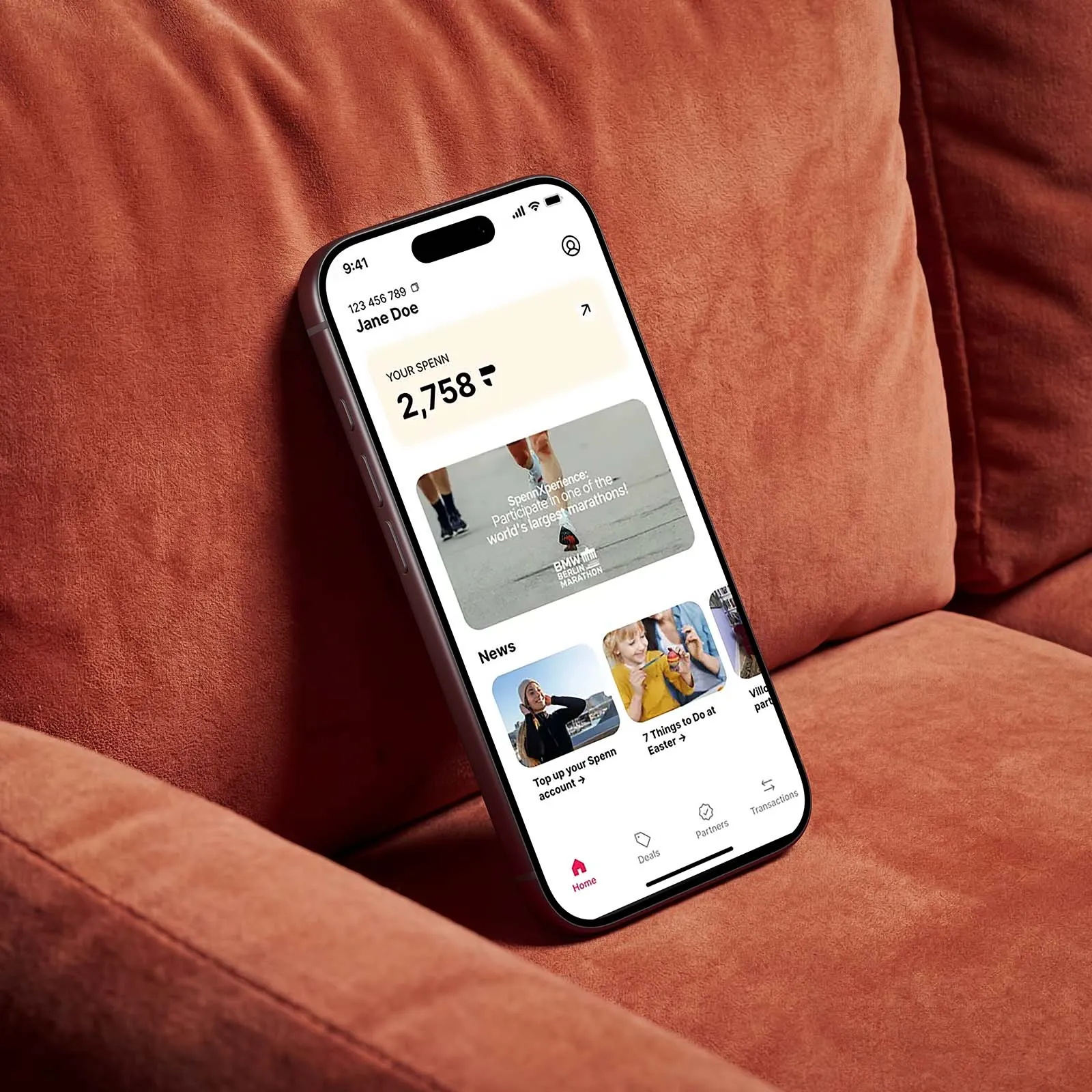 A mobile phones rests on a brown chair, displaying the Spenn app.