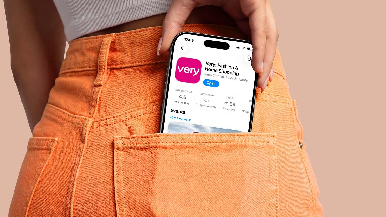 A phone displaying the Very app peeks out the back pocket of a pair of orange jeans.