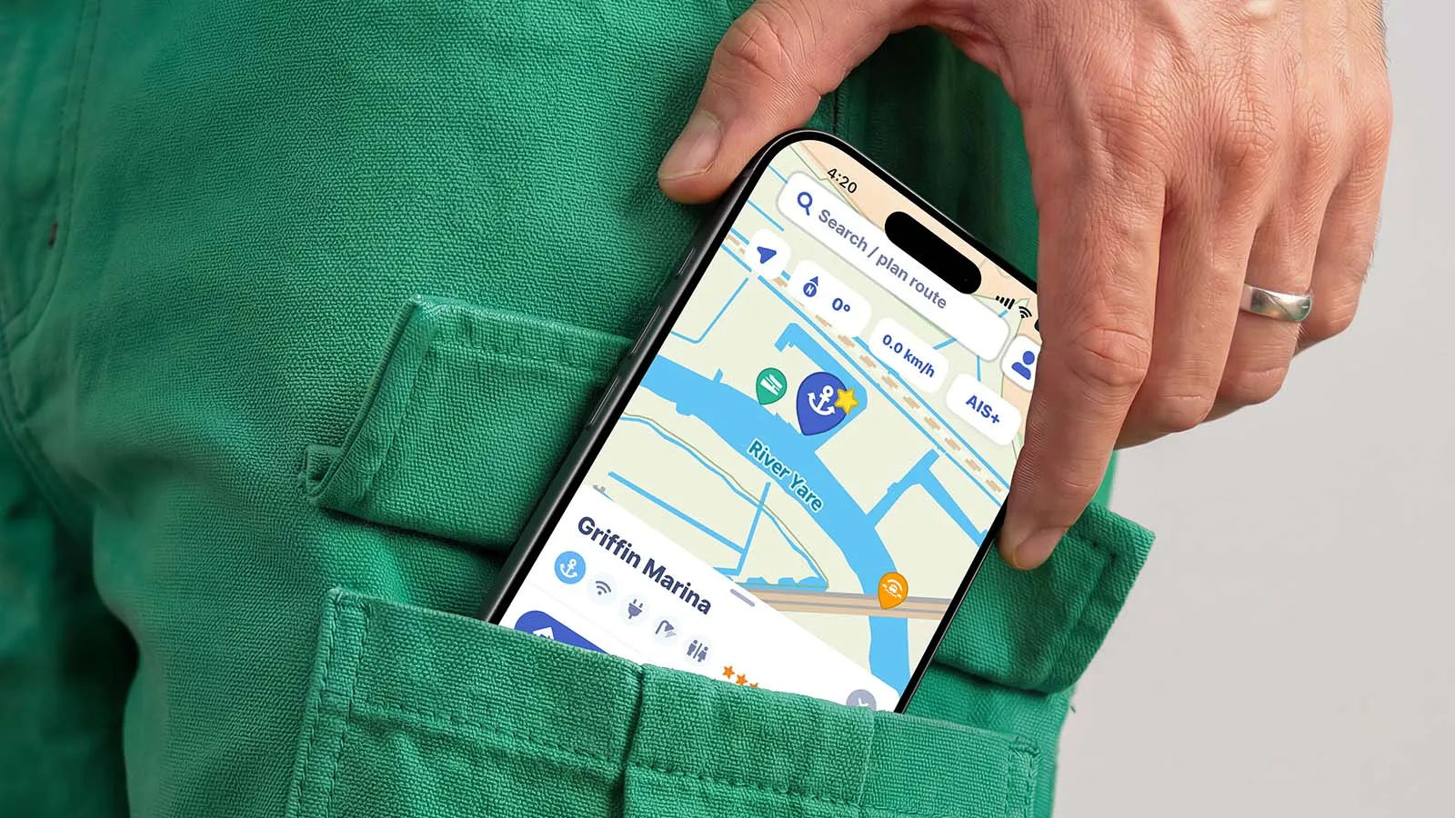 An iPhone peeks out of the pocket of a pair of green shorts, showing a live map from the Waterkaarten app.