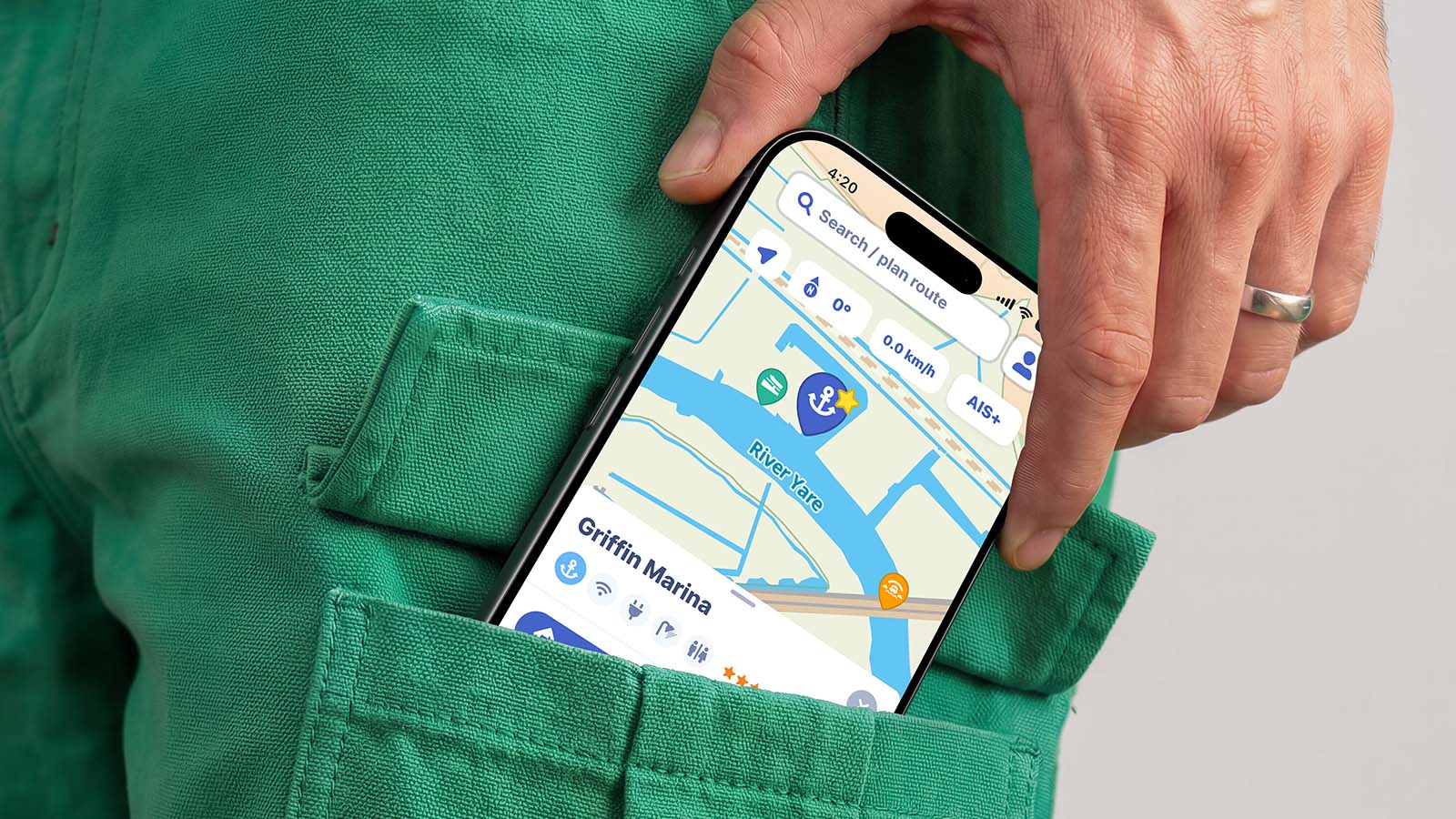 An iPhone peeks out of the pocket of a pair of green shorts, showing a live map from the Waterkaarten app.