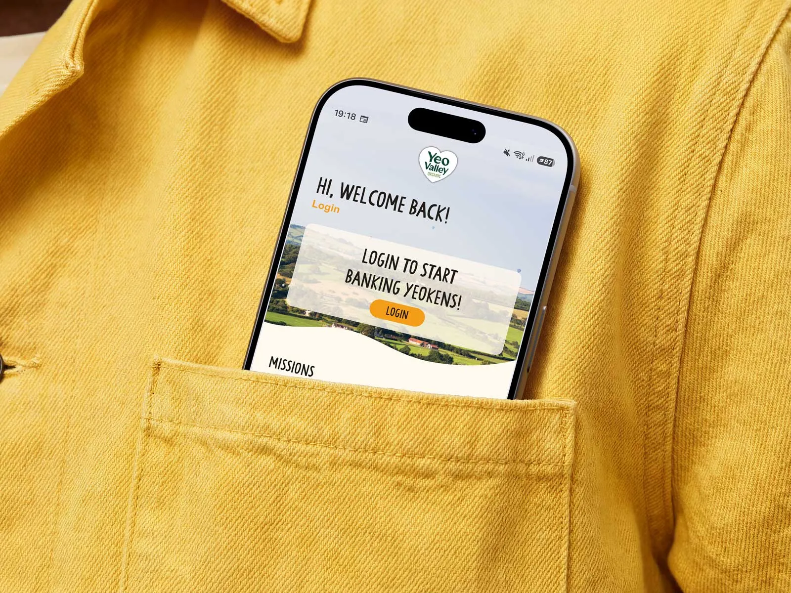 A phone displaying the Yeo Valley app peeks out of the top pocket of a yellow shirt.