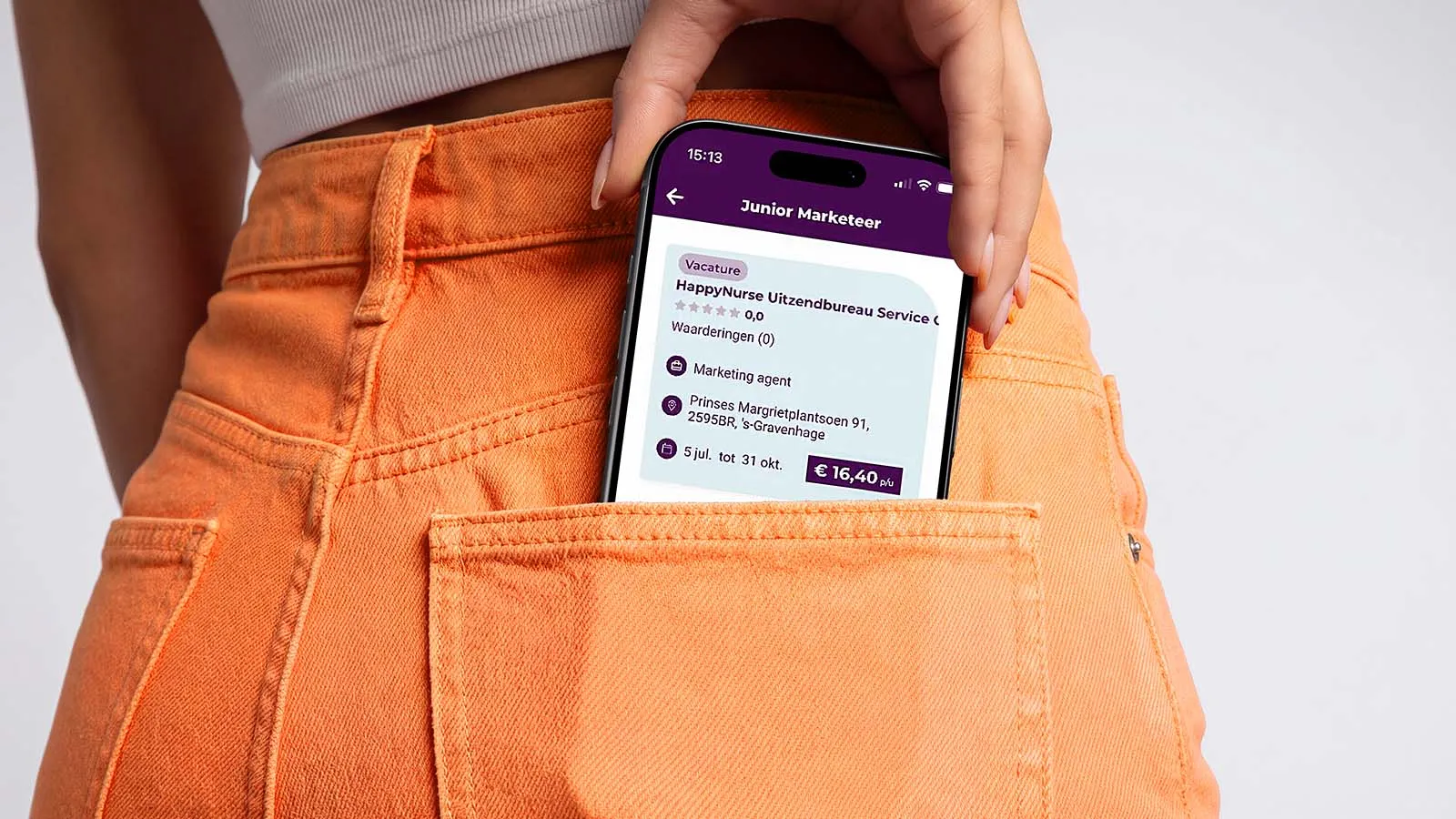 A phone showing the Youbahn app peeks out of the back pocket of a pair of orange jeans.