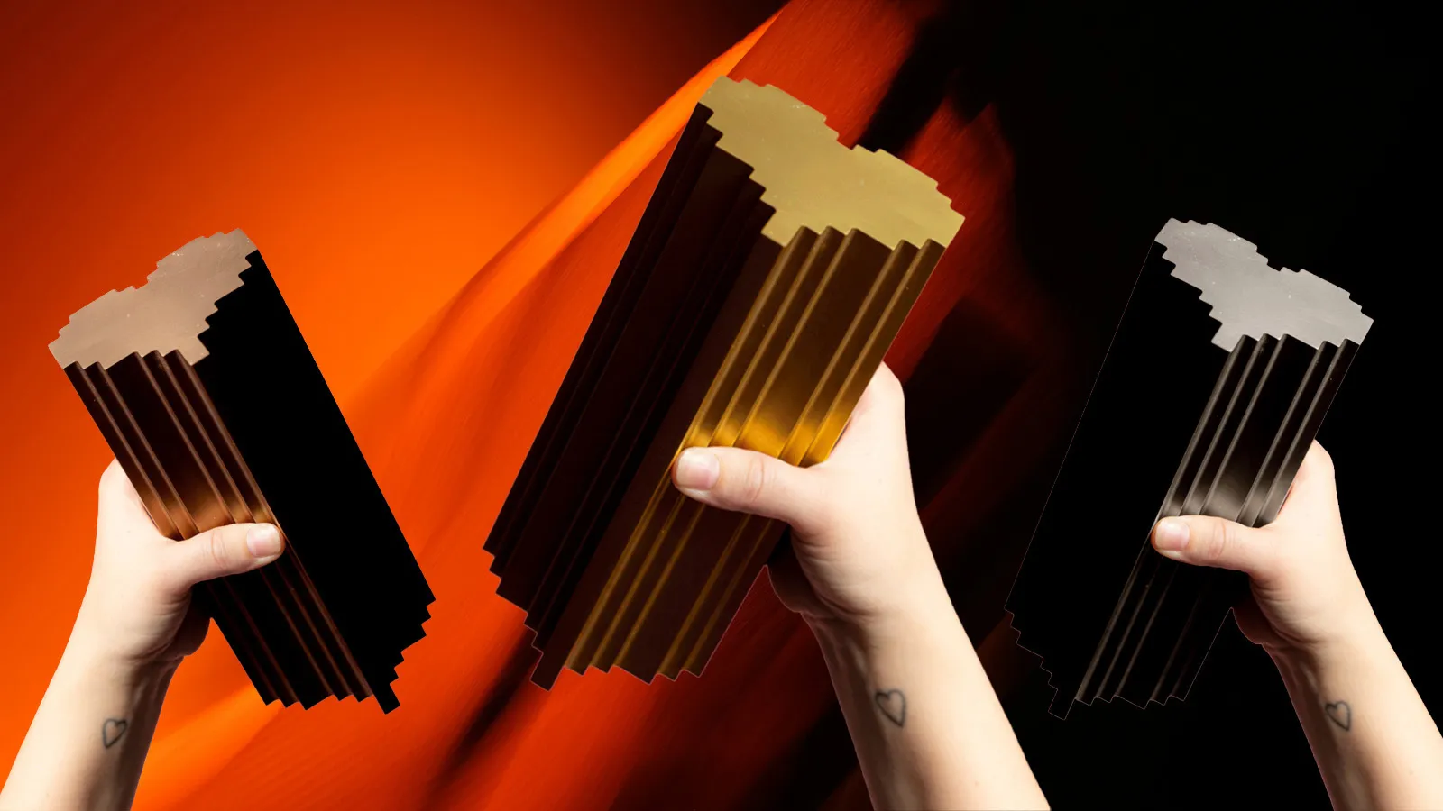 Three hands hold a Bronze, Silver, and Gold Lovie award against a red background.